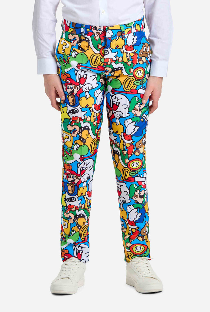 Image of teen wearing a Super Mario all-over print suit, consisting of blazer, pants and tie. Main color is blue, but there is also yellow, red and white. Pants close up.