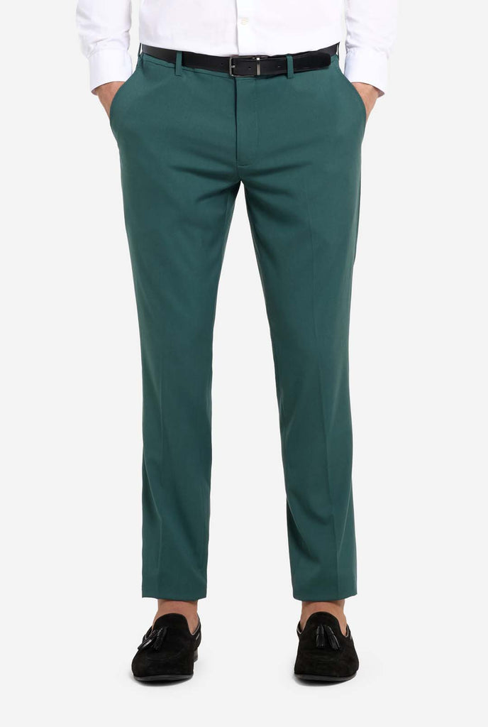 Image with light grey background and man wearing dark green men’s suit and white shirt. Suits consists of blazer and pants. Pants close up.