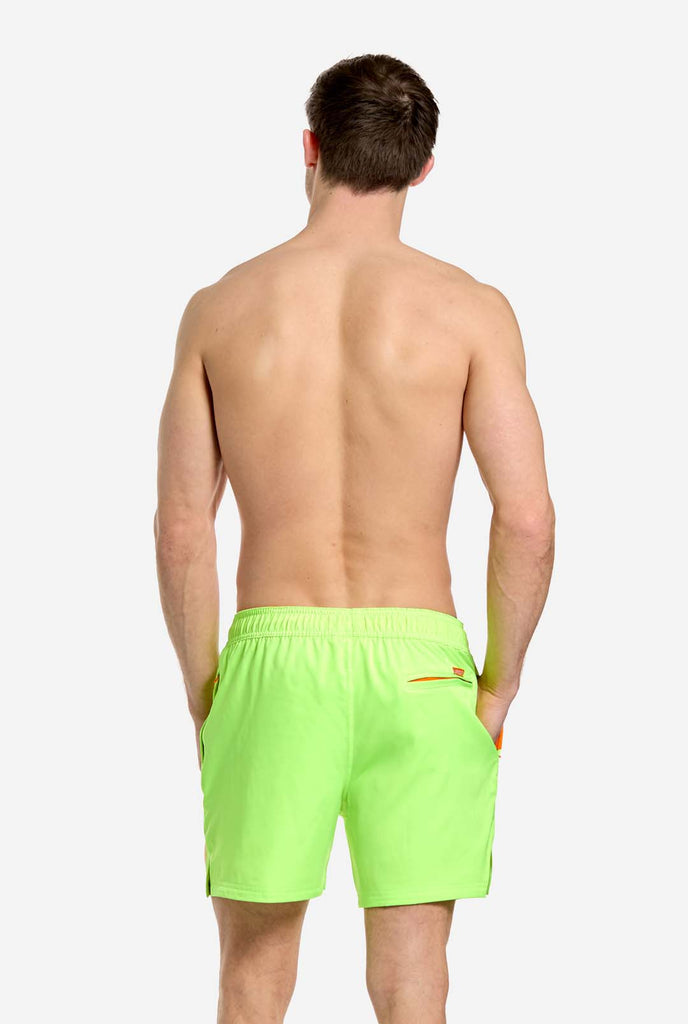 Man wearing Neon lime green swim trunks for men, view from the back