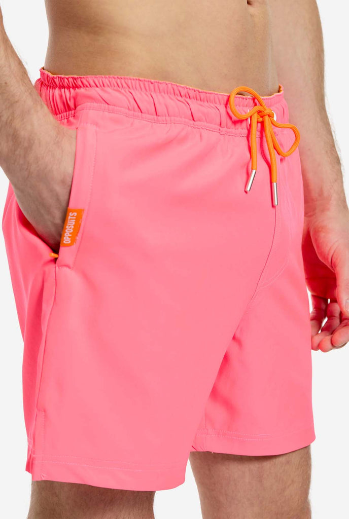 Man wearing Neon Pink Power swim trunks for men, close up