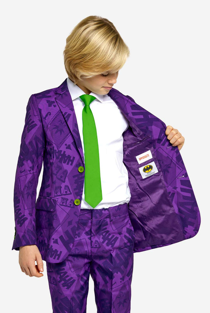 Teen wearing purple teen boys suit with a The Joker theme. Further he is wearing a green tie and a with shirt. He is showing the inside of the jacket.