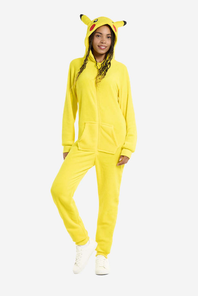 A woman is wearing a vibrant Pikachu onesie, designed to resemble the iconic Pokémon character. This unisex adult onesie is bright yellow with Pikachu’s recognizable face on the hood, featuring large black-tipped ears, black eyes, red cheeks, and a cute smile. The onesie has a convenient front zipper closure and two front pockets for functionality and comfort. The soft, cozy material makes it perfect for lounging, cosplay events, or Pokémon-themed gatherings. Ideal for Pokémon fans.