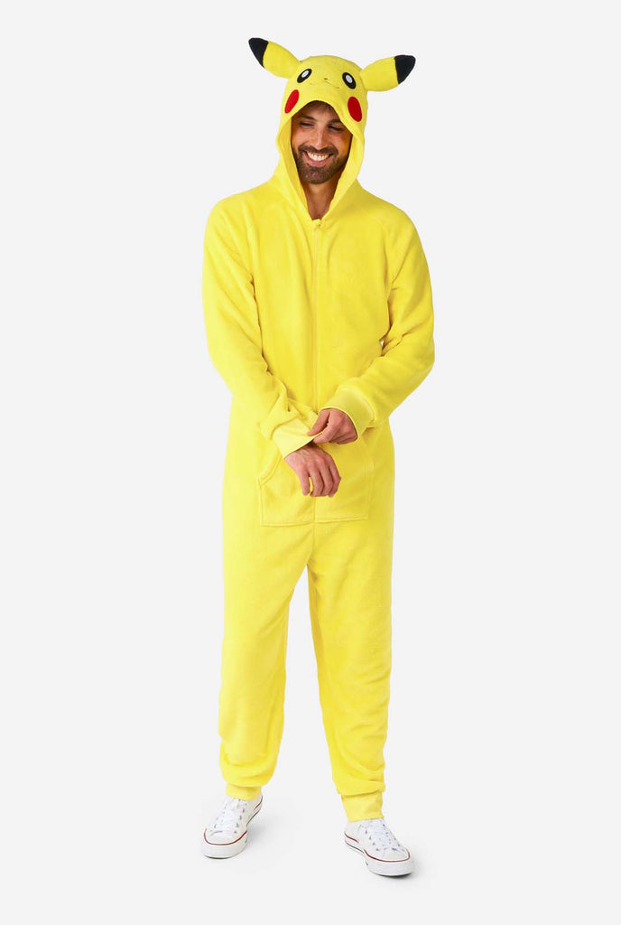 A man is wearing a vibrant Pikachu onesie, designed to resemble the iconic Pokémon character. This unisex adult onesie is bright yellow with Pikachu’s recognizable face on the hood, featuring large black-tipped ears, black eyes, red cheeks, and a cute smile. The onesie has a convenient front zipper closure and two front pockets for functionality and comfort. The soft, cozy material makes it perfect for lounging, cosplay events, or Pokémon-themed gatherings.