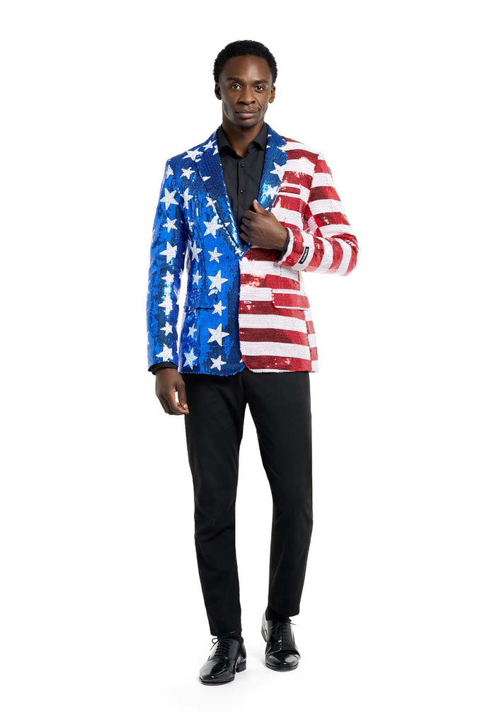 Image with white background and man wearing USA flag-colored red, blue and white sequins blazer. The man is also wearing black shirt and black pants. Full body image.