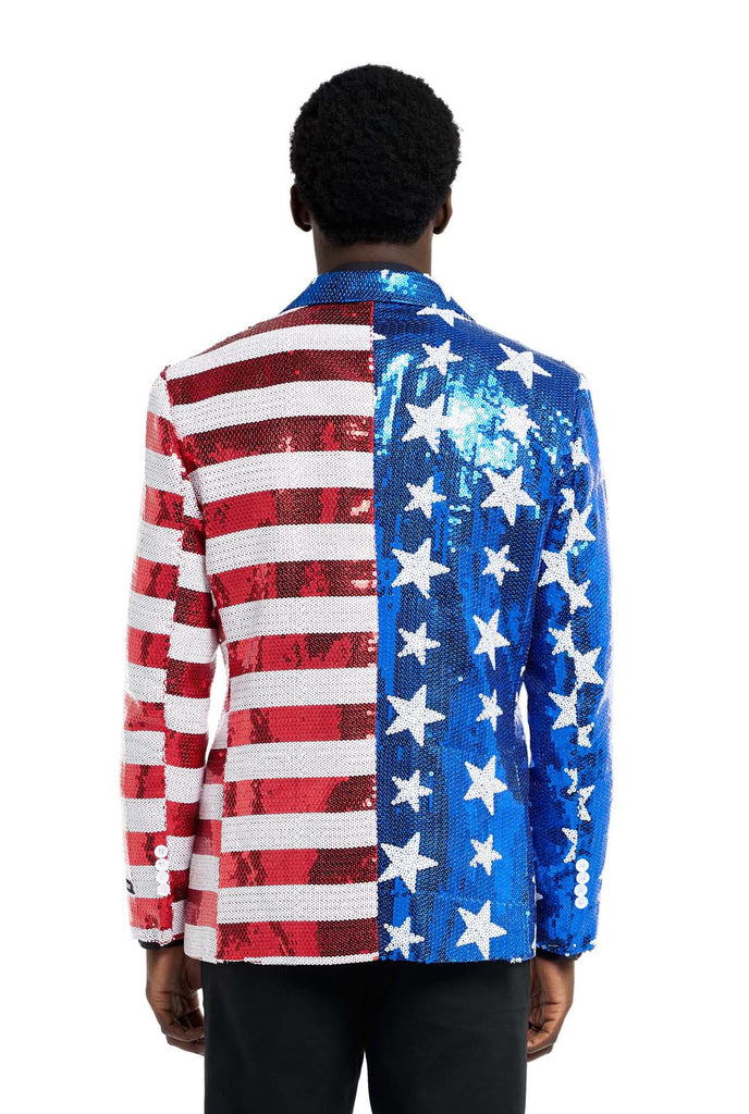 Image with white background and man wearing USA flag-colored red, blue and white sequins blazer. The man is also wearing black shirt and black pants. View from the back.