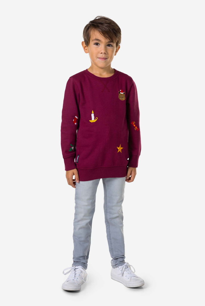 Kid wearing burgundy red Christmas sweater with Christmas icons