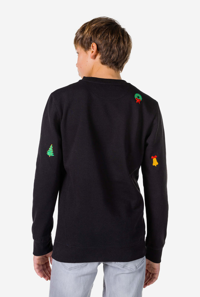 Teen wearing black Christmas sweater with Christmas icons, view from the back