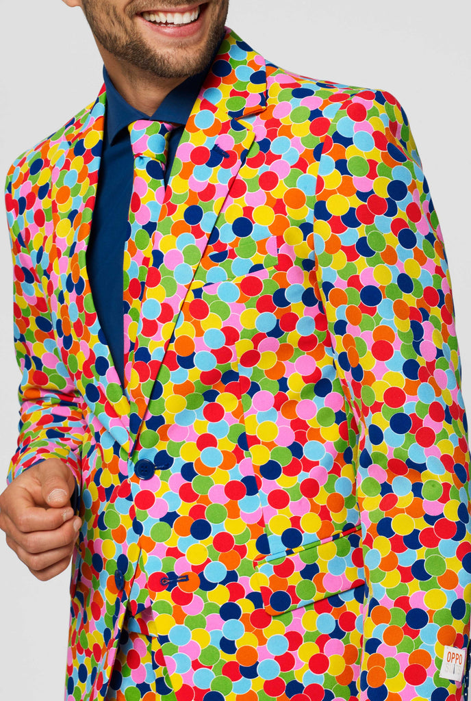 Man wearing men's suit with confetti print and blue dress shirt, close up