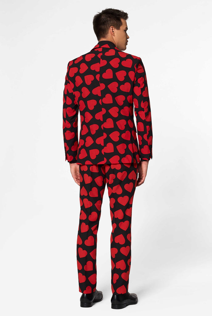 Man wearing black suit with red hearts print, view from the back