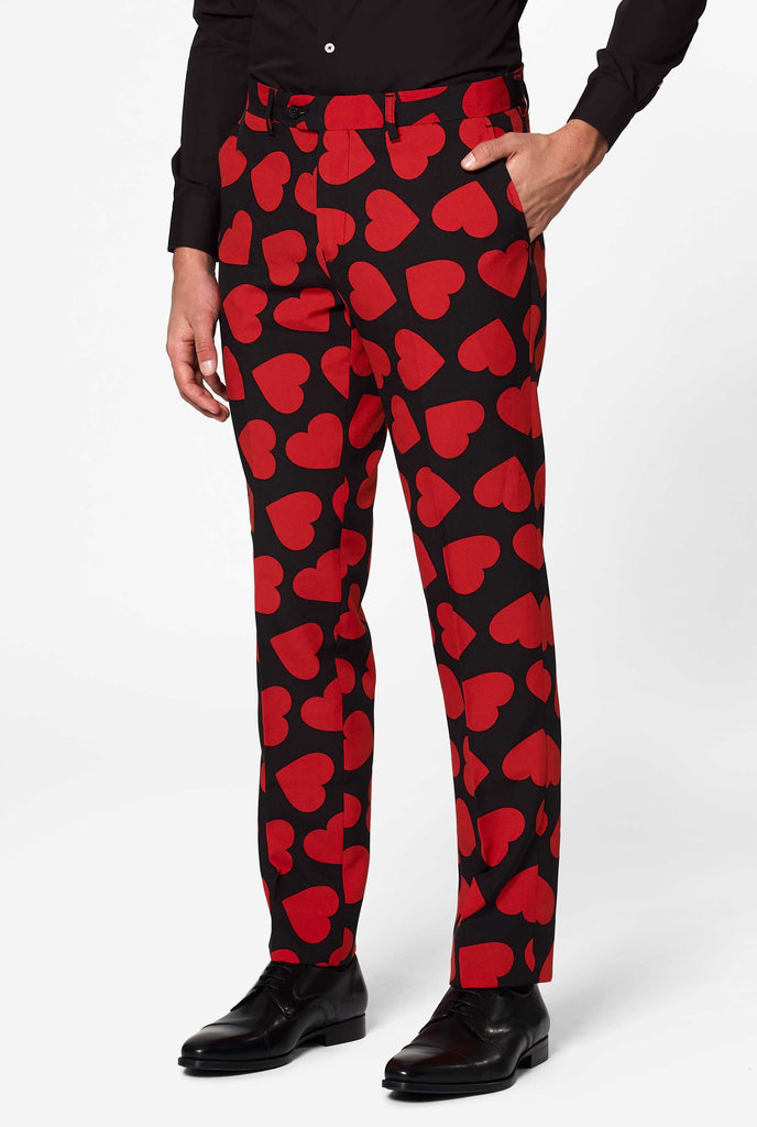 Man wearing black suit with red hearts print, pants close up