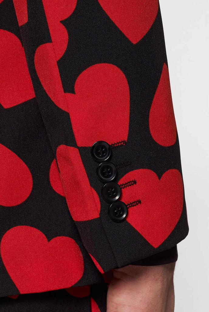 Man wearing black suit with red hearts print, sleeve close up