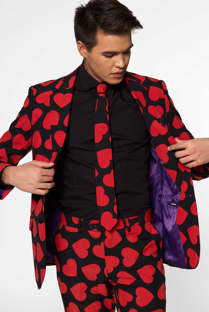 Man wearing black suit with red hearts print