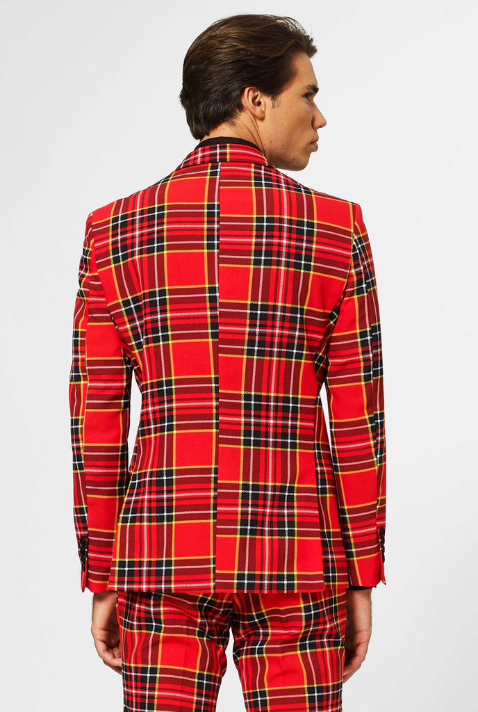 Man wearing red Christmas tartan men's suit, view from the back