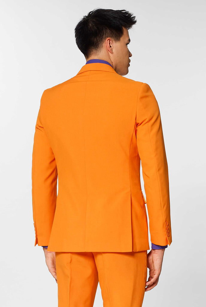 Man wearing orange men's suit with purple dress shirt, view from the back