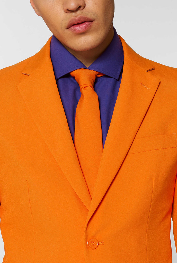 Man wearing orange men's suit with purple dress shirt, close up