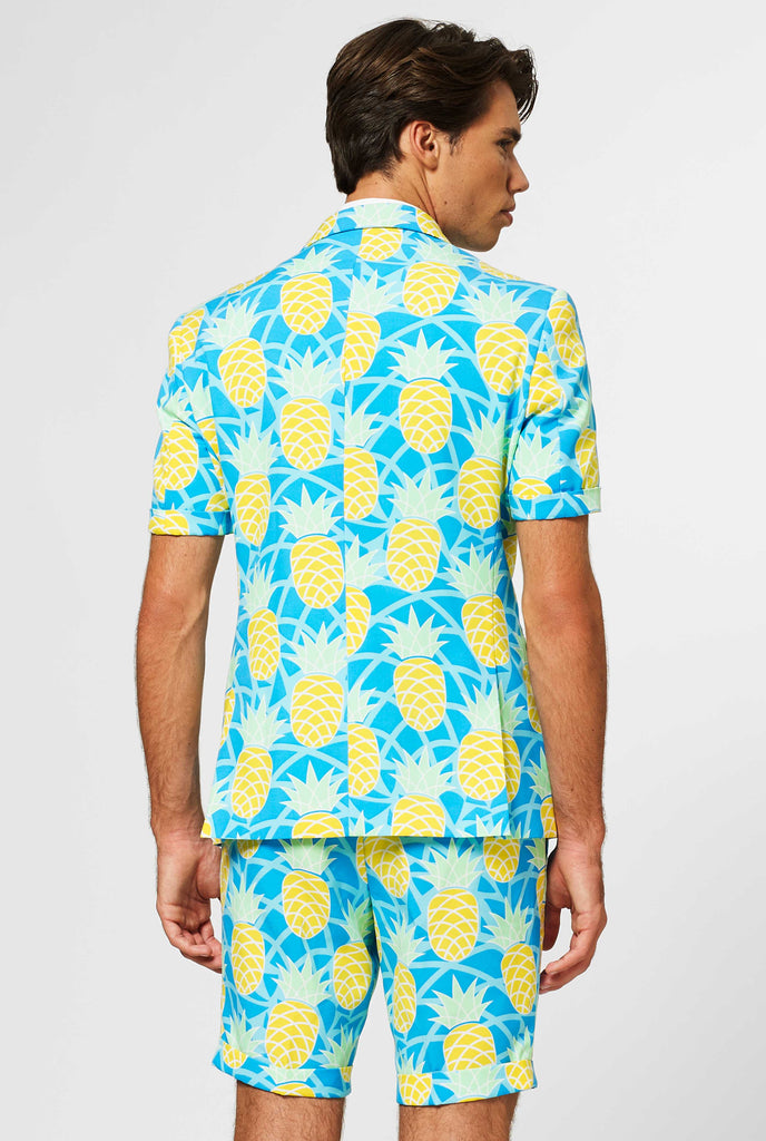 Man wearing blue summer suit with pineapple print, view from the back