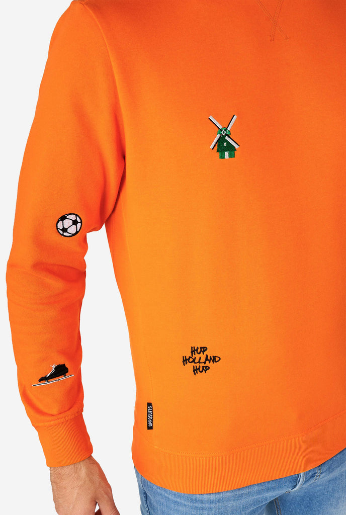 Man wearing orange sweater with Dutch icons, close up