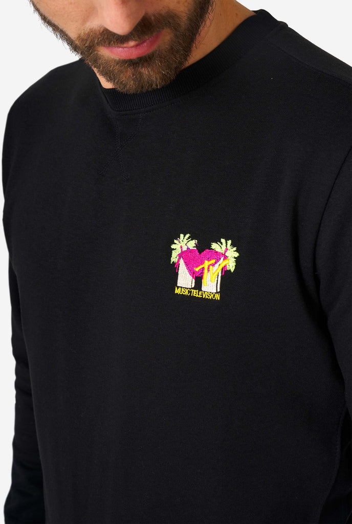 Man wearing black sweater with MTV embroidery, close up