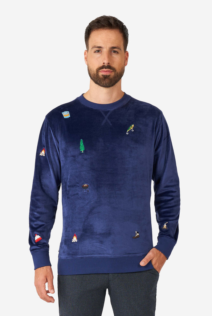 Man wearing velvet blue Christmas sweater with Christmas icons