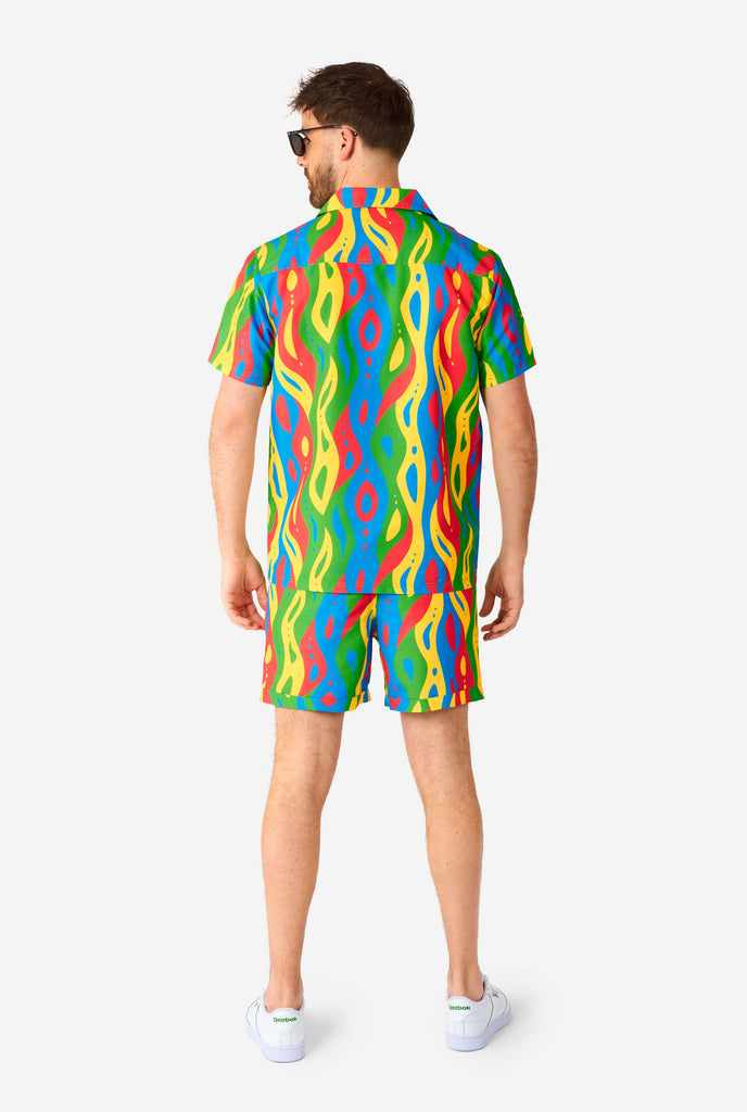 Man wearing colorful summer set, consisting of shirt and shorts.