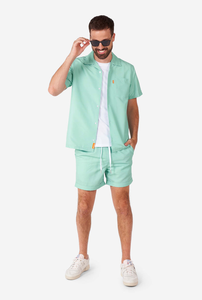 Man wearing green summer set, consisting of short sleeve shirt and shorts.