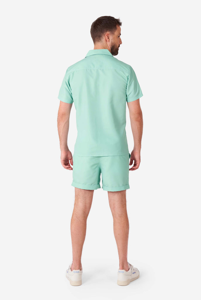 Man wearing green summer set, consisting of short sleeve shirt and shorts.