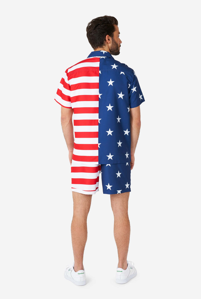 Man wearing summer outfit, consisting of shirt and shorts, with USA flag print, view from the back