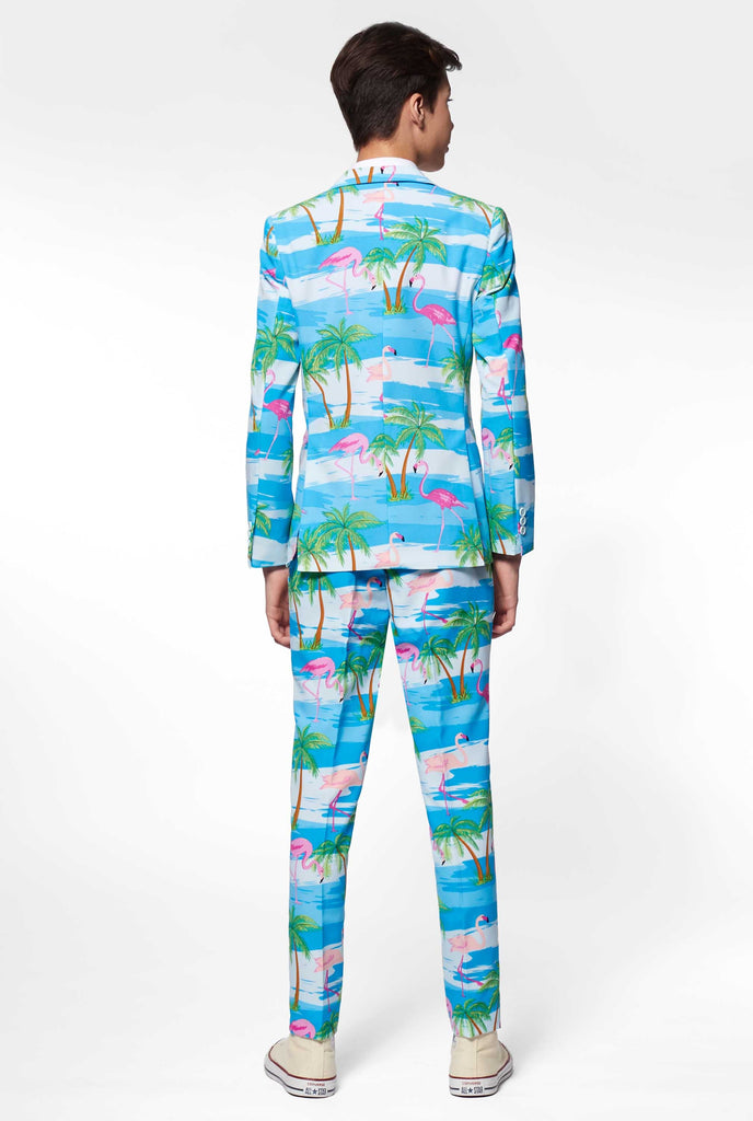 Teen wearing light blue suit with flamingo palm tree print, view from the back