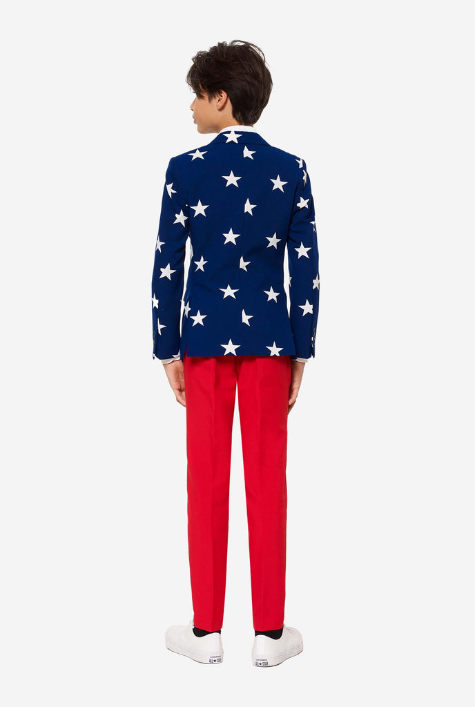 Teen wearing formal USA themed fourth of July suit, consisting of blue jacket and red pants. 